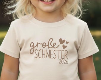 Camiseta "Hermana Mayor 2026", color crema con corazones | Anuncio de embarazo | Personalizable con el texto y nombre que desees.