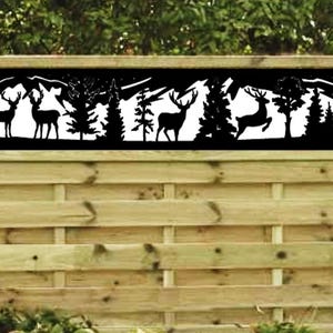 May include: A black metal fence panel with a cut-out design of deer and trees. The panel is mounted on a wooden fence.