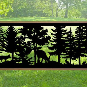 May include: A black metal outdoor screen featuring a forest scene with trees, a fox, a deer, and a rabbit. The screen is framed by two wooden posts and set against a green grassy background.