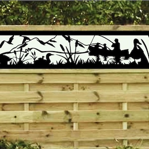 May include: Black metal fence panel with a cut-out design of a lake scene with birds, reeds, and people in a boat. The scene is set against a mountain backdrop.