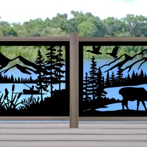 May include: Two black metal decorative fence panels with a nature scene cut-out design. The design includes mountains, trees, a lake, deer, and flying birds. The panels are framed in a light brown wood and set against a backdrop of a lake and trees.