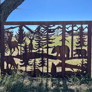 May include: A metal silhouette of a forest scene with deer, bears, and trees. The silhouette is cut out of a rusty metal sheet and is mounted on a wooden frame.