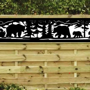 May include: Black metal fence panel with a cut-out design of bears and trees. The panel is mounted on a wooden fence.