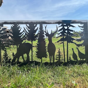 May include: Metal silhouette wall art featuring a deer, elk, and two birds in a forest setting. The art is cut out of metal and has a black finish.