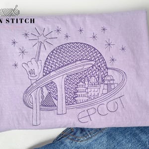 May include: A purple t-shirt with an embroidered design of the Epcot Center in Orlando, Florida. The design includes the iconic Spaceship Earth, the monorail, and the words "Epcot" in a stylized font.