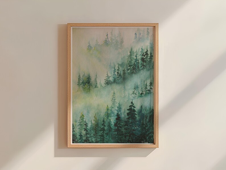 May include: A framed watercolor painting of a misty forest scene with green trees and a light blue sky. The painting is in a light wood frame.