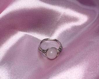 May include: A silver wire wrapped ring with a pink rose quartz stone.