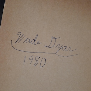 May include: A handwritten inscription in blue ink on a tan paper background. The inscription reads "Wade Dyar" above the year "1980". The handwriting is cursive and the numbers are simple.
