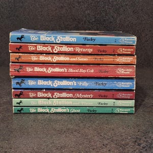 May include: A stack of eight vintage "The Black Stallion" books by Farley. The book spines are in various colors, including blue, red, orange, and green. Each book features the title, author's name, and publisher, Random House.