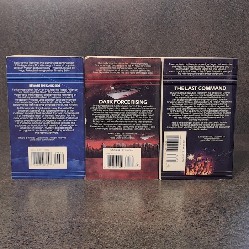 Op de afbeelding: Drie Star Wars-romans worden getoond, met titels als "Beware the Dark Side" en "Dark Force Rising". De boeken hebben kleurrijke covers met tekst en afbeeldingen, tegen een donkere achtergrond. De ruggen zijn zichtbaar en tonen de branding van de serie.