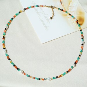 May include: A colorful beaded necklace with a star charm. The necklace features green, orange, black, and white beads.