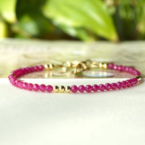 Può includere: Un braccialetto delicato realizzato con piccole perline di rubino rosso sfaccettate e distanziatori dorati.