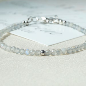 Könnte beinhalten: Ein zartes silbernes Armband mit einem einzelnen silbernen Perlenakzent, bestehend aus einer Reihe von hellblauen Edelsteinperlen.