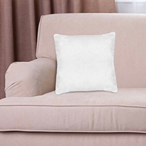 May include: A white square throw pillow on a light beige sofa.