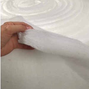 May include: A white, fluffy, rolled up batting material. The batting is soft and has a slightly textured surface.
