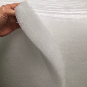 May include: A white roll of batting material, a type of polyester fiberfill used for crafts, quilting, and upholstery.
