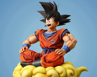 Puede incluir: Figura de un personaje de Dragon Ball Z sentado en una nube amarilla. El personaje viste un gi naranja con una camiseta interior y muñequeras azules. La figura tiene el pelo negro puntiagudo y está sonriendo. La nube es de color amarillo brillante.