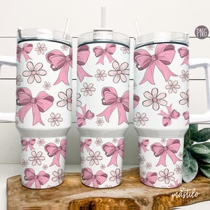 May include: Three white stainless steel tumblers with pink bows and flowers on a white background. The tumblers have lids and straws.