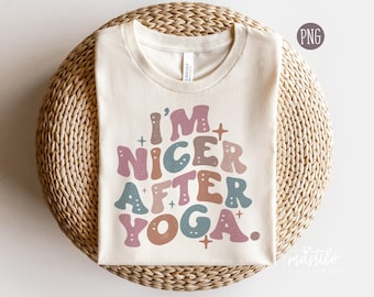 May include: A cream-colored short-sleeve t-shirt featuring the text I'M NICER AFTER YOGA in a wavy, multi-colored font. The letters are colored in muted shades of pink, blue, and brown, accented with small star and heart shapes.