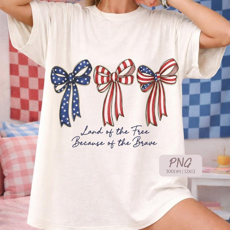 Peut inclure: T-shirt cr&egrave;me avec trois motifs de n&oelig;uds patriotiques rouges, blancs et bleus. Les n&oelig;uds pr&eacute;sentent des motifs d'&eacute;toiles et de rayures. Le texte "Land of the Free Because of the Brave" est en dessous.
