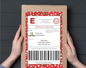 Może przedstawiać: Brązowe kartonowe pudełko z świąteczną czerwoną i białą etykietą. Etykieta głosi "Express Elf Delivery" i zawiera tekst "The Elf Team Santa Workshop" oraz kod kreskowy. Pudełko jest trzymane przez dwie ręce.