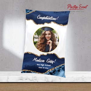 May include: A blue and gold graduation party favour bag with a photo of a graduate in a cap and gown. The bag says "Congratulations!" and "Madison Curry!" with the text "Any High School Class of 20xx".