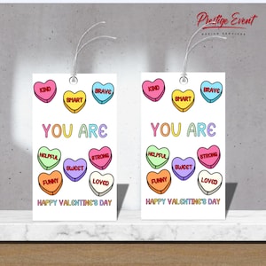 May include: Two white gift tags with a string, featuring colorful candy hearts with words like "Kind," "Smart," and "Brave." The text "You Are" and "Happy Valentine's Day" are also displayed.