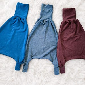 Op de afbeelding: Drie broeken met een hoge tailleband in coltruistijl en boorden bij de enkels. De broeken zijn uitgevoerd in effen blauw, gemêleerd blauw en gemêleerd bordeauxrood, elk met een losvallend ontwerp met een verlaagd kruis en toelopende pijpen.