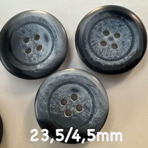 Könnte beinhalten: Eine Sammlung großer, runder Knöpfe mit einem marmorierten schwarz-weißen Design. Jeder Knopf hat vier Löcher und misst etwa 23,5 mm im Durchmesser. Geeignet für verschiedene Näh- und Bastelprojekte.