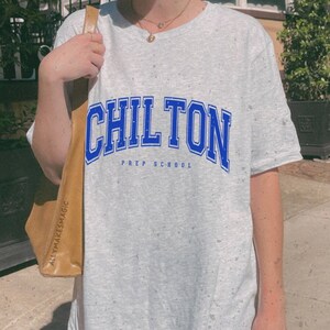 Könnte beinhalten: Ein graues T-Shirt mit einem blauen und weißen Aufdruck, auf dem "Chilton Prep School" steht.