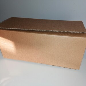 May include: A brown cardboard box with a corrugated top. The box is closed and appears to be empty.