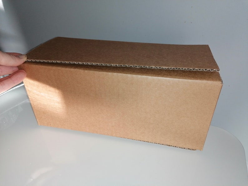 May include: A brown cardboard box with a corrugated top. The box is closed and appears to be empty.