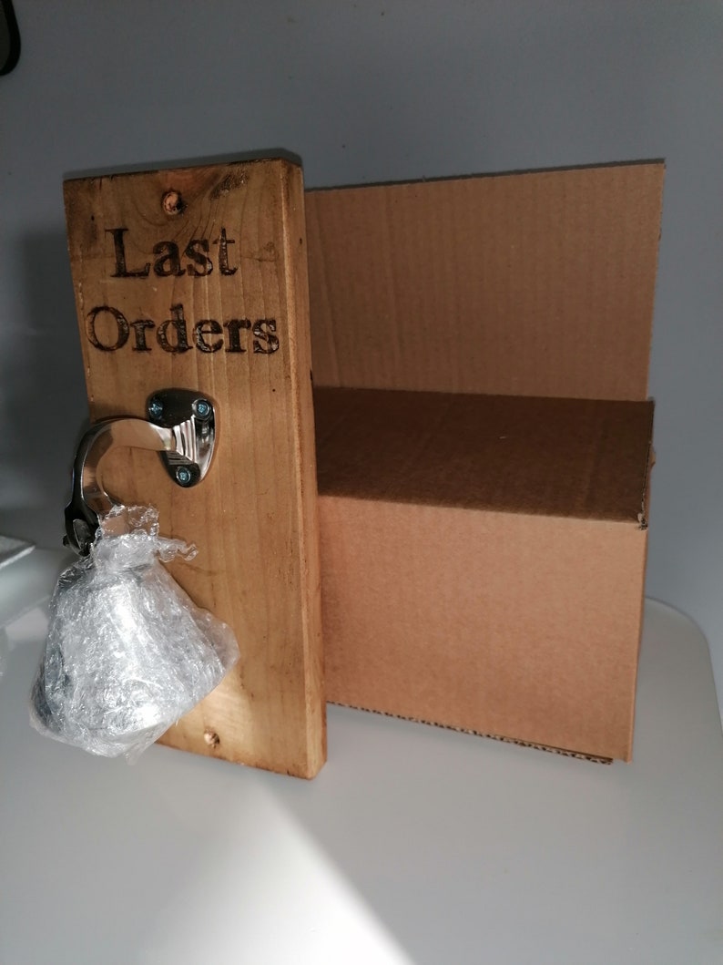 May include: A wooden sign with the text "Last Orders" engraved on it. A silver bell is attached to the sign with a metal hook.