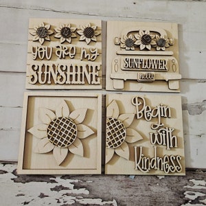 Puede incluir: Cuatro letreros de madera con diseños de girasoles y camiones. Los letreros dicen "You are my sunshine", "Sunflower hello" y "Begin with kindness".