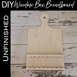 May include: An unfinished light-colored wooden breadboard with a handle featuring a hole for hanging and a scalloped-edge pocket attached to the front. The text DIY Window Box Breadboard and UNFINISHED is visible in the image.