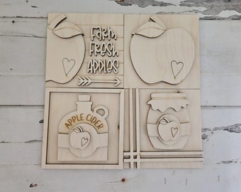 May include: Four wooden signs with a farmhouse theme. The top left sign has a red apple with a heart and the text "Farm Fresh Apples". The top right sign has a red apple with a heart. The bottom left sign has a bottle with the text "Apple Cider" and a red apple with a heart. The bottom right sign has a jar with a red apple with a heart.