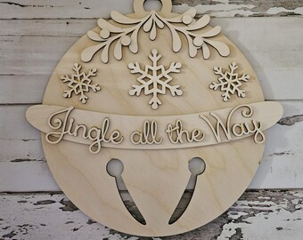 Puede incluir: Adorno navideño de madera con forma de campana con el texto "Jingle all the way" y copos de nieve.