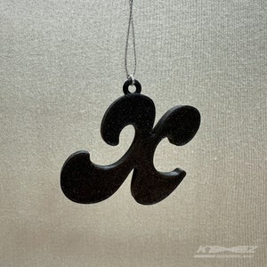 May include: Black glitter ornament shaped like the letter "K" hanging from a silver string.