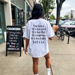 May include: White t-shirt with black text that reads "I'm tired, It's too cold, It's too hot, It's raining, It's too late, Let's Go".