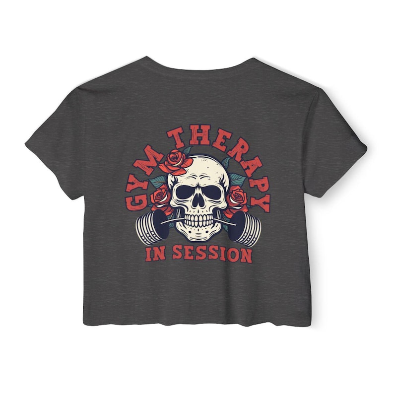 May include: Dark gray cropped t-shirt with a skull graphic wearing a barbell in its mouth. The skull is surrounded by red roses and the text "Gym Therapy In Session".