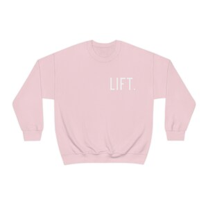 May include: A pink sweatshirt with the word "LIFT." printed in white on the front.