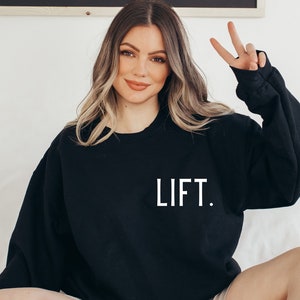 May include: Black sweatshirt with the word "LIFT." printed in white on the front.