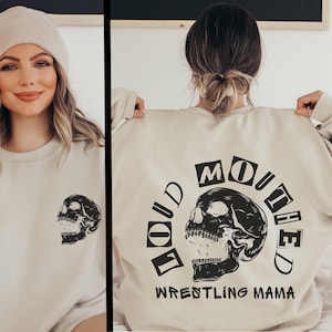 May include: A beige sweatshirt with a black skull graphic and the text "You'd  Mouthed" and "Wrestling Mama".