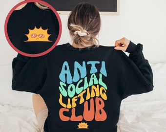 May include: Black sweatshirt with a rainbow colored graphic that says "Anti Social Lifting Club". A small sun with sunglasses is on the bottom of the graphic and another sun with sunglasses is on the left shoulder of the sweatshirt.