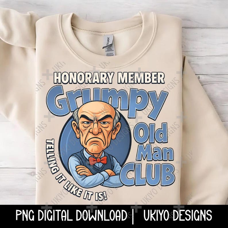 May include: A beige sweatshirt featuring a cartoon illustration of a grumpy old man with the text "Grumpy Old Man Club." The design includes the words "Honorary Member" and "Telling it like it is!" in blue and white.