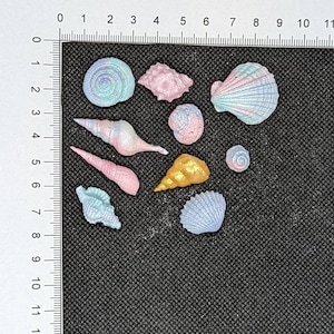 May include: Assortment of colourful seashells in various shapes and sizes. The shells are made of a smooth, glossy material and have an iridescent finish.