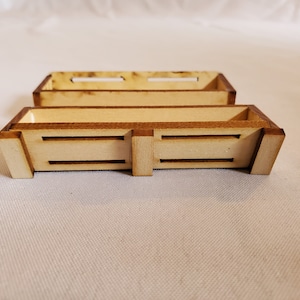 May include: Two wooden boxes stacked on top of each other. The boxes are made of light brown wood and have a natural finish. The boxes have a rectangular shape and are open on one side.