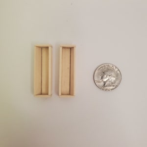 May include: Two small, rectangular wooden boxes, each with a single compartment. The boxes are about the size of a quarter.