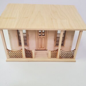 Peut inclure: Une maison de poup&eacute;e en bois avec un porche avant, deux fen&ecirc;tres et une porte. Le porche a une balustrade d&eacute;corative.