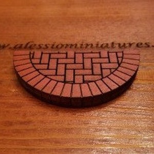 May include: A half-round brick pathway made of red bricks with a brick pattern in the center.